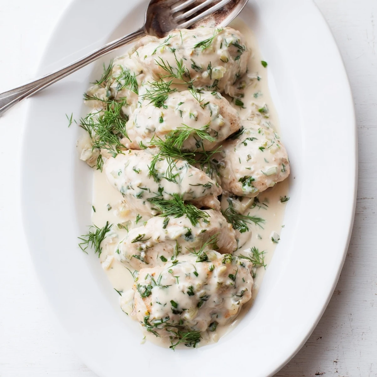 Savory creamy dill chicken plated with sauce drizzled over tender cooked meat