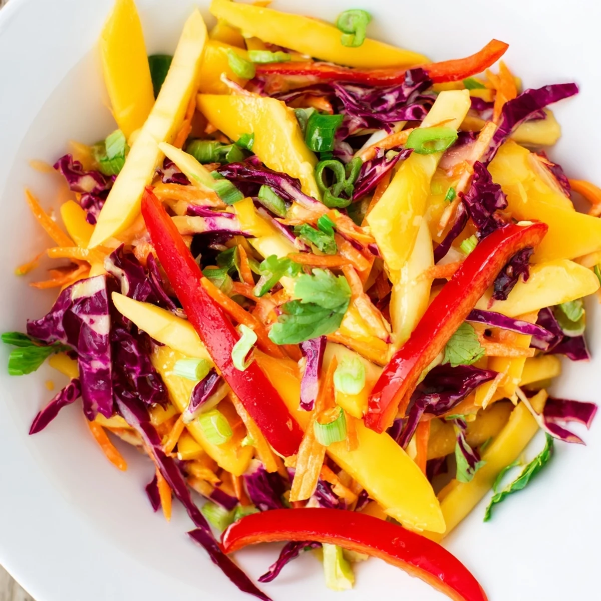 Tangy mango slaw featuring julienned vegetables and toasted peanuts for summer grilling sides