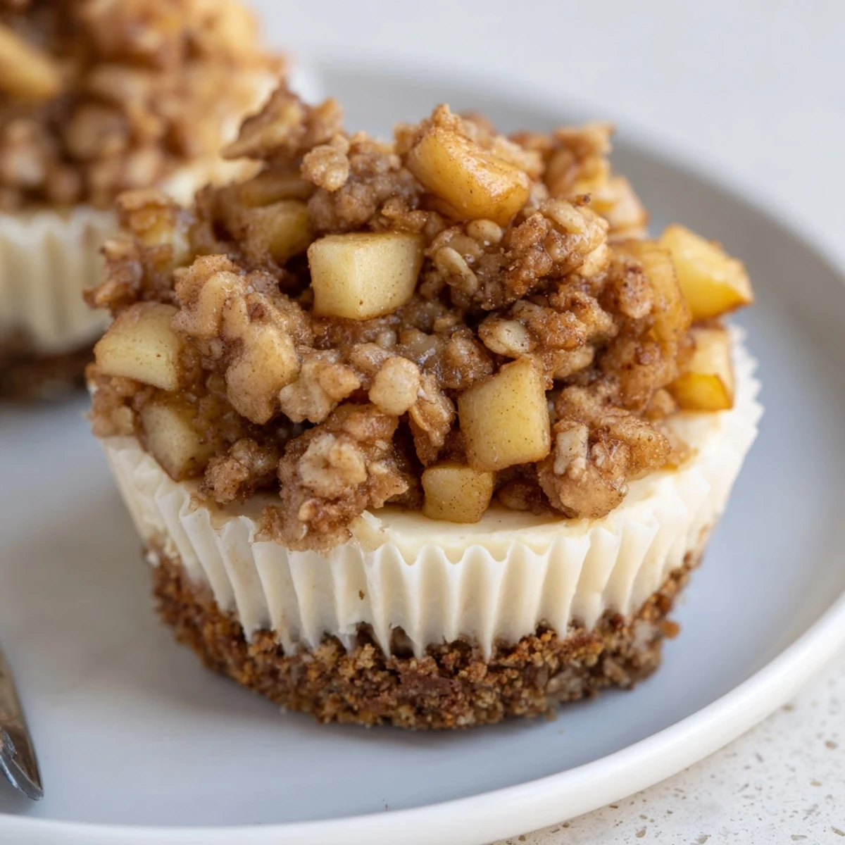 Mini apple cheesecakes featuring tender baked apples, buttery oat crumble, and smooth cream cheese filling