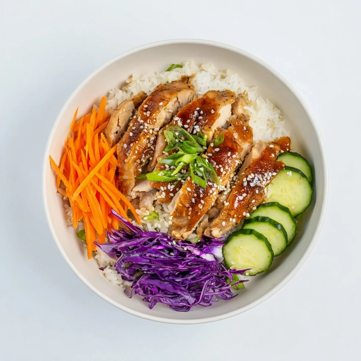Vibrant Korean BBQ chicken bowl with marinated sliced thighs atop colorful purple cabbage cucumber and shredded carrots