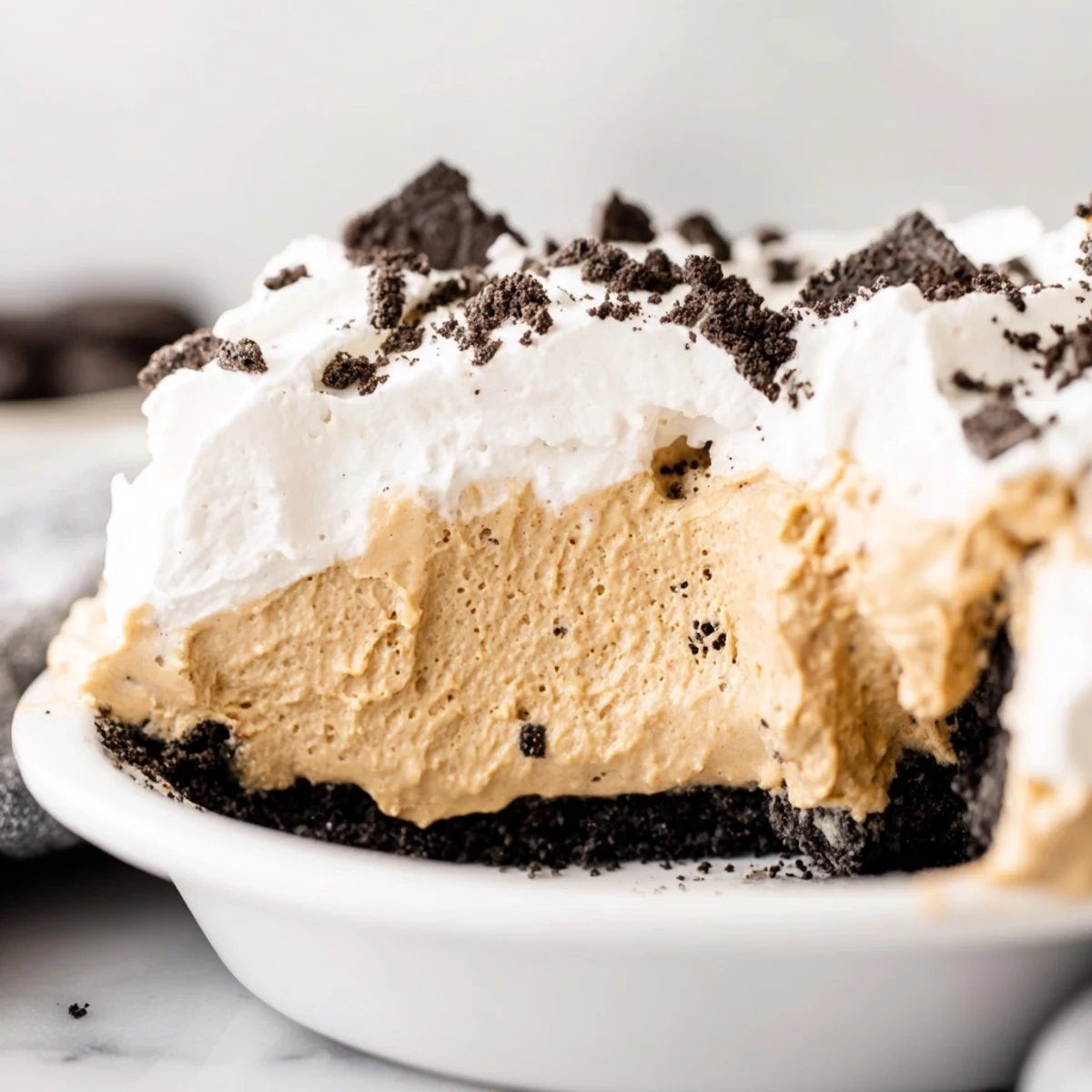 Creamy peanut butter Oreo pie with whipped topping and cookie crumbles on chocolate crust