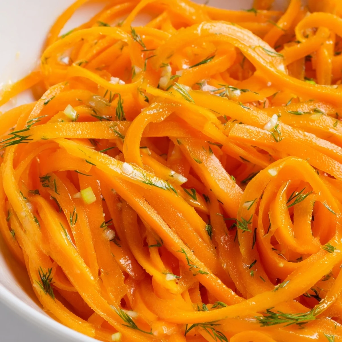 Marinated Lemon Dill Carrot Salad in a serving bowl with fresh herb garnish and glossy citrus dressing