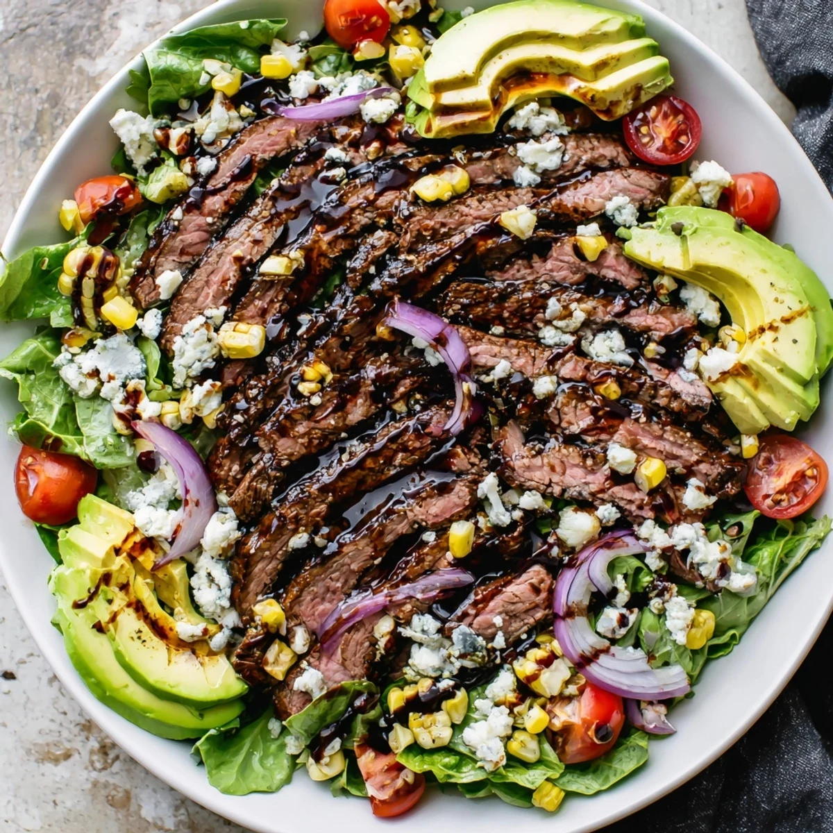 Balsamic steak Gorgonzola salad drizzled with vinaigrette, topped with avocado and grilled corn kernels