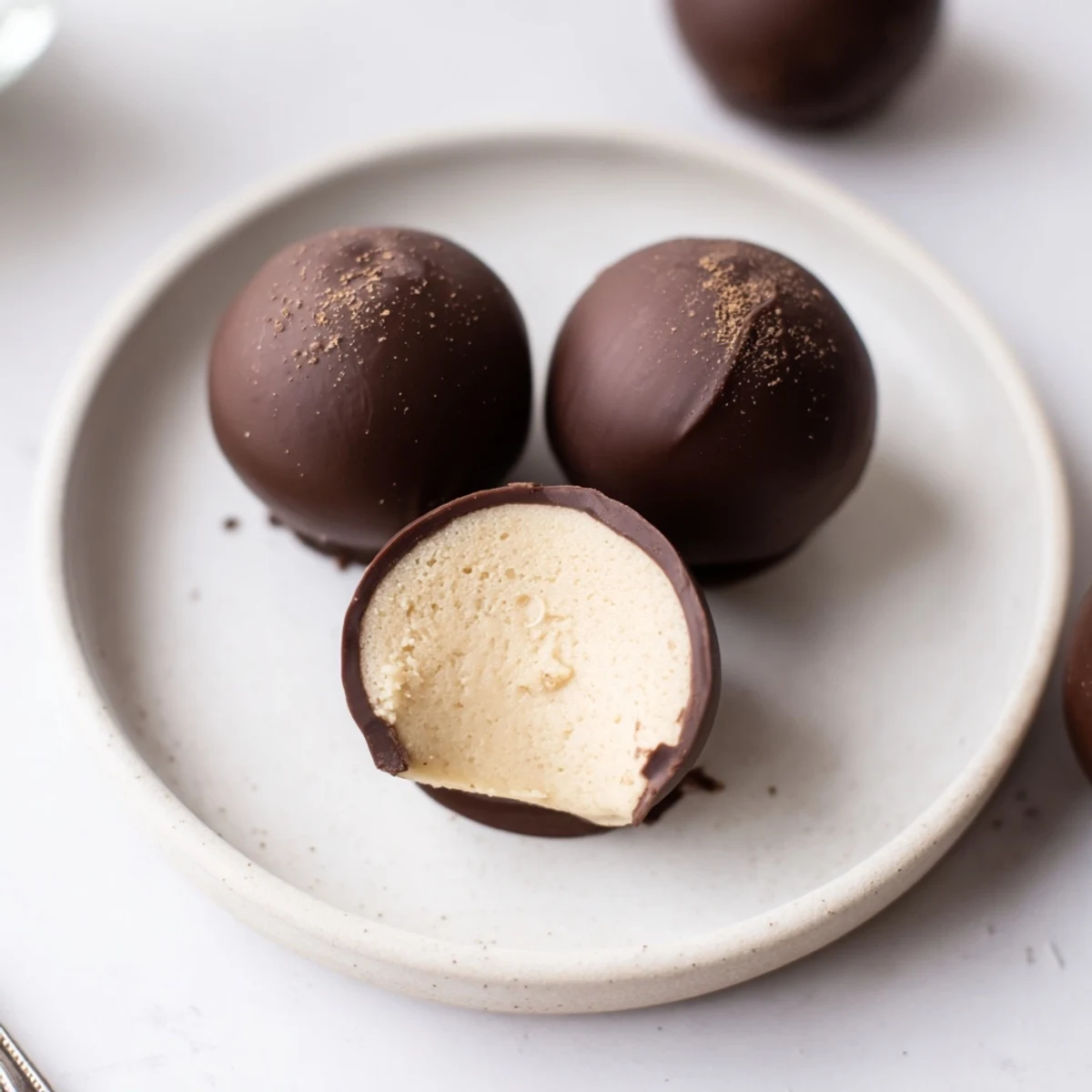 A plateful of Dark Chocolate Eggnog Truffles, creamy centers peeking through