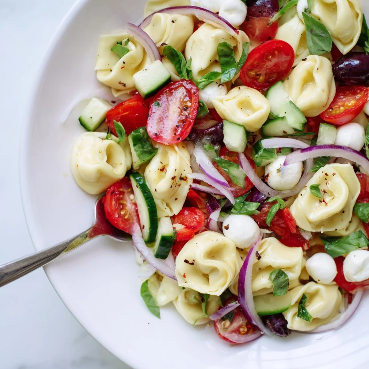 Tortellini Pasta Salad with bright tomatoes and basil, chilled for picnic