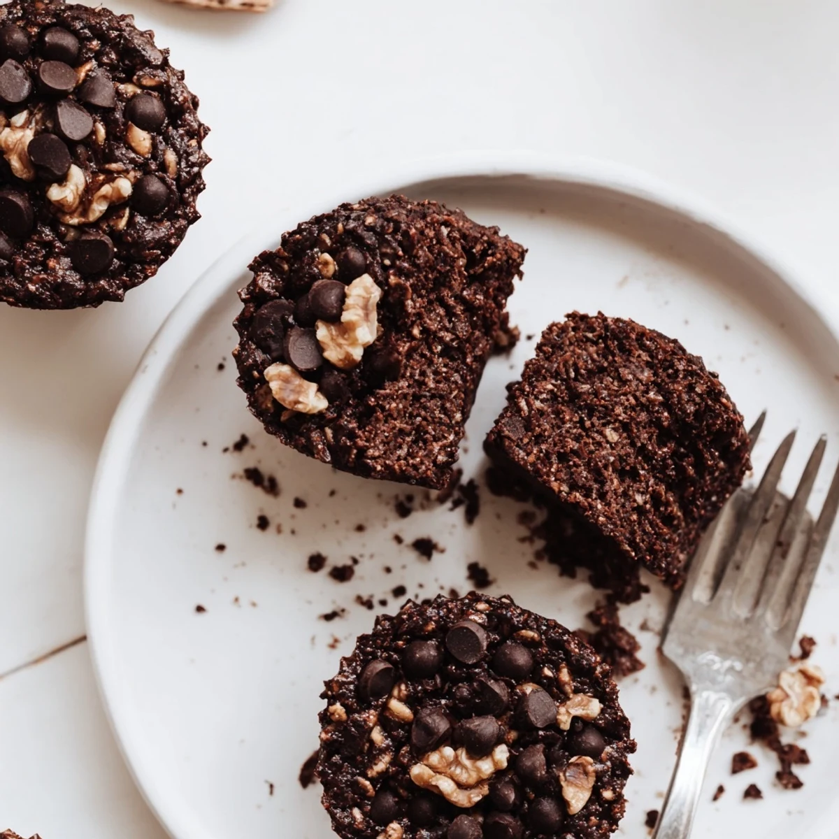 Moist chocolate oatmeal muffins studded with dark chocolate chips cooling in a lined muffin tin