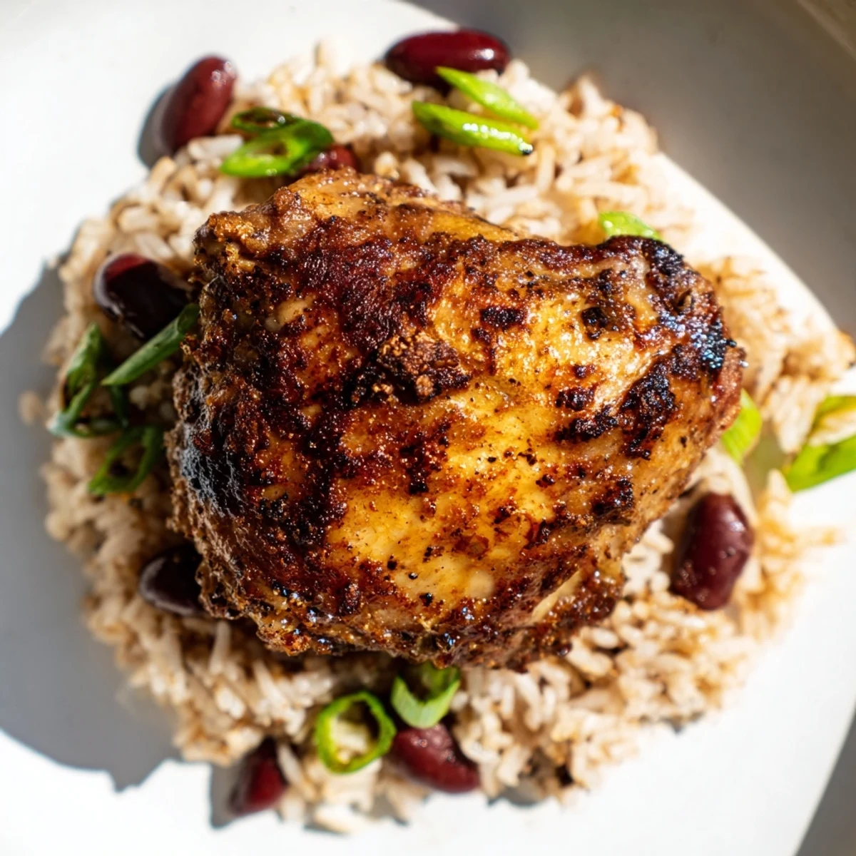 Spicy Caribbean jerk chicken served over aromatic coconut rice and beans garnished with green onions