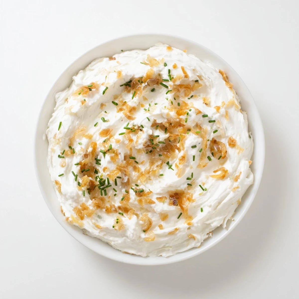 Rich French onion dip garnished with green onions alongside vegetable crudités