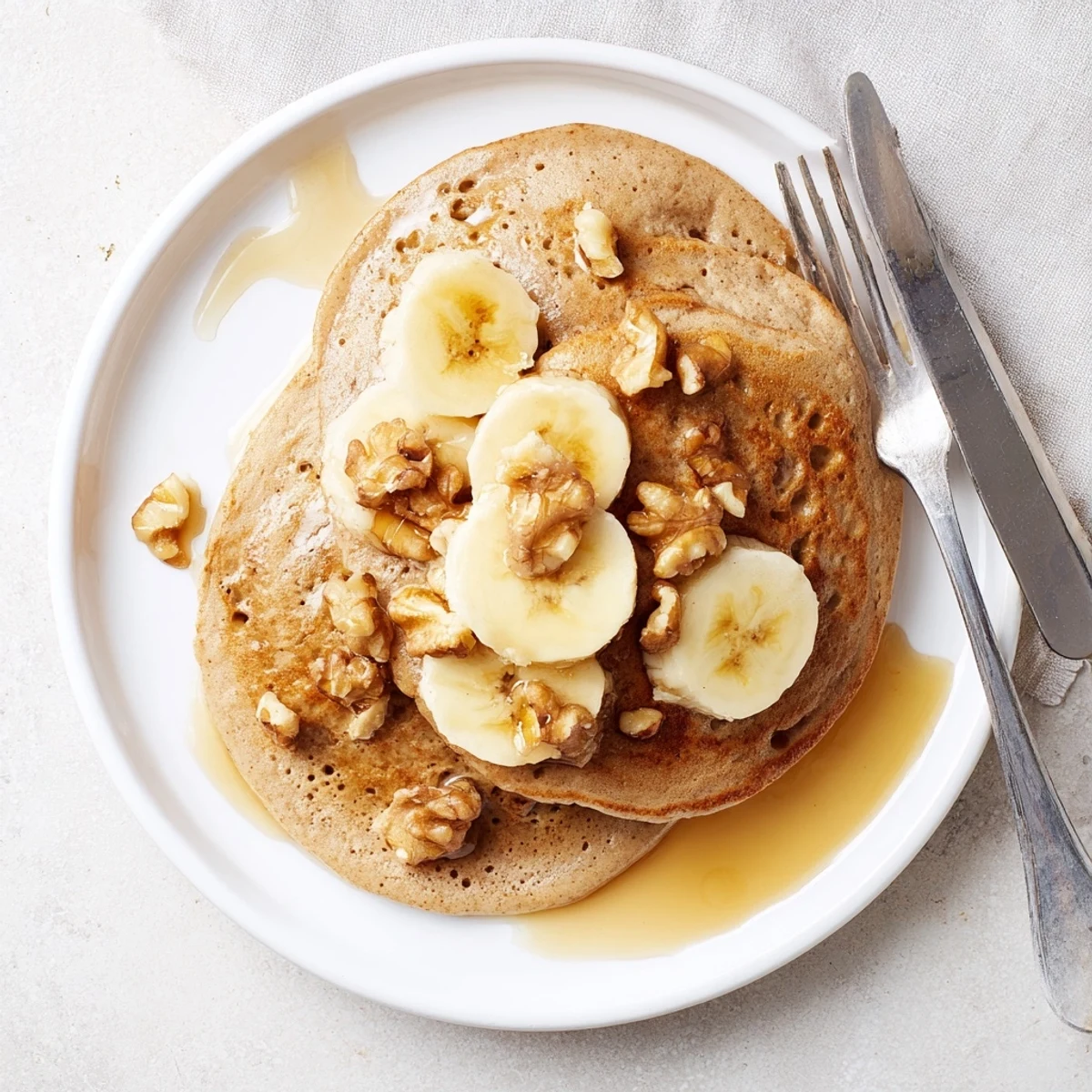 Healthy protein banana pancakes cooking on a griddle with bubbles forming on the surface