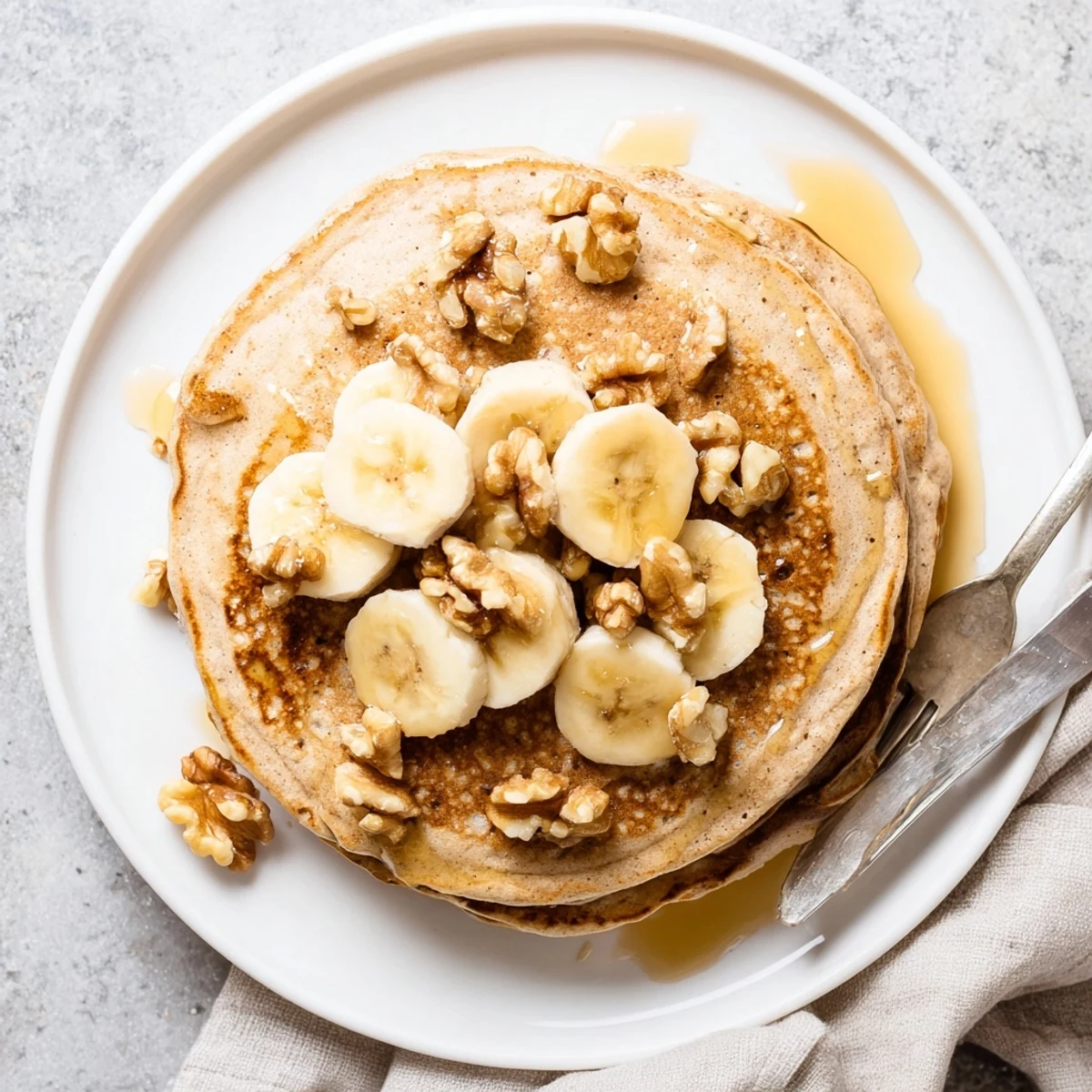 Golden stack of fluffy protein banana pancakes topped with fresh berries and maple syrup