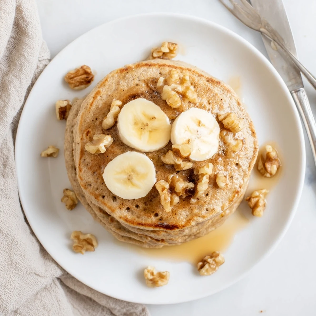 Stack of warm protein banana pancakes served with walnuts and drizzled with honey
