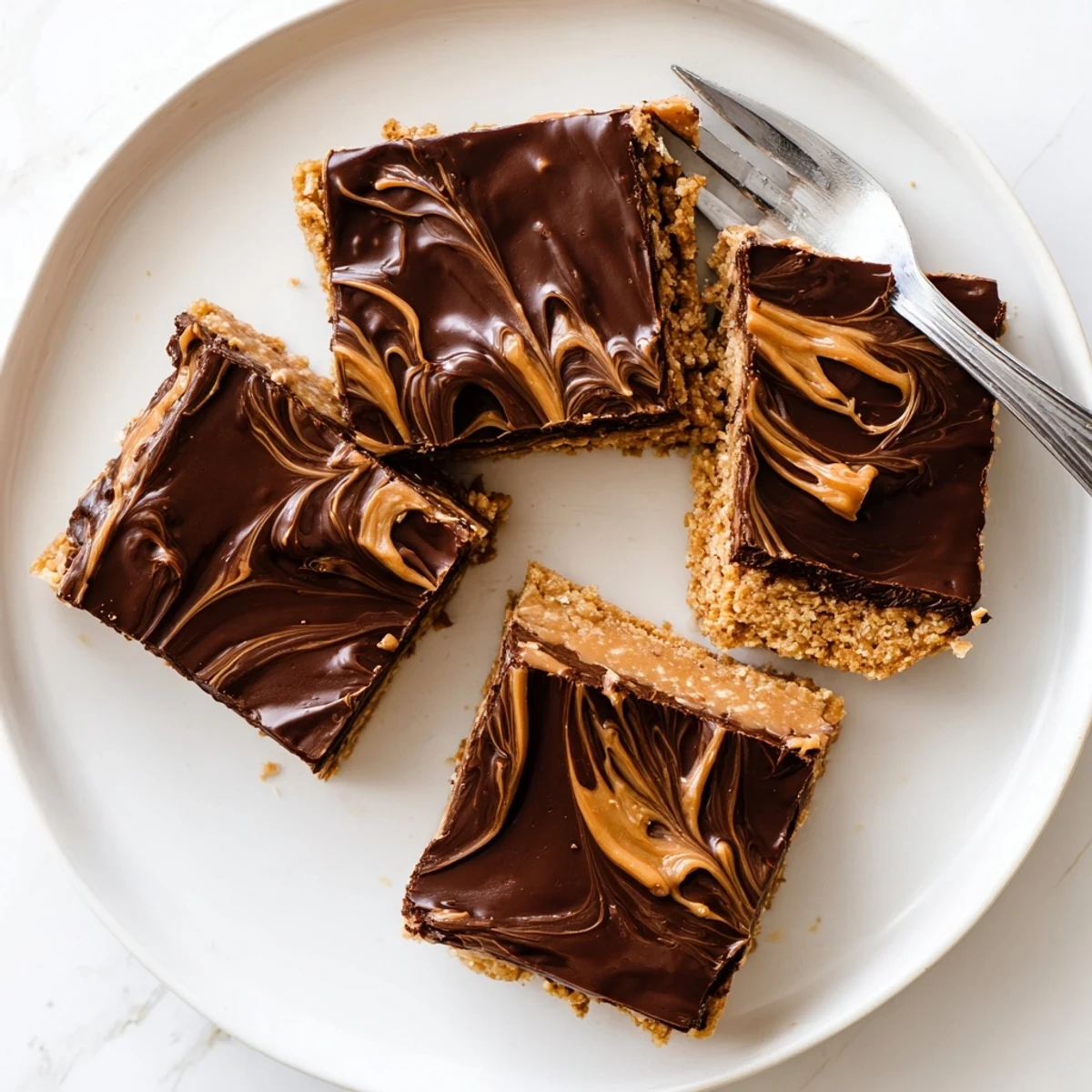 Rich peanut butter bars featuring glossy chocolate ganache and graham cracker crust, cut into squares