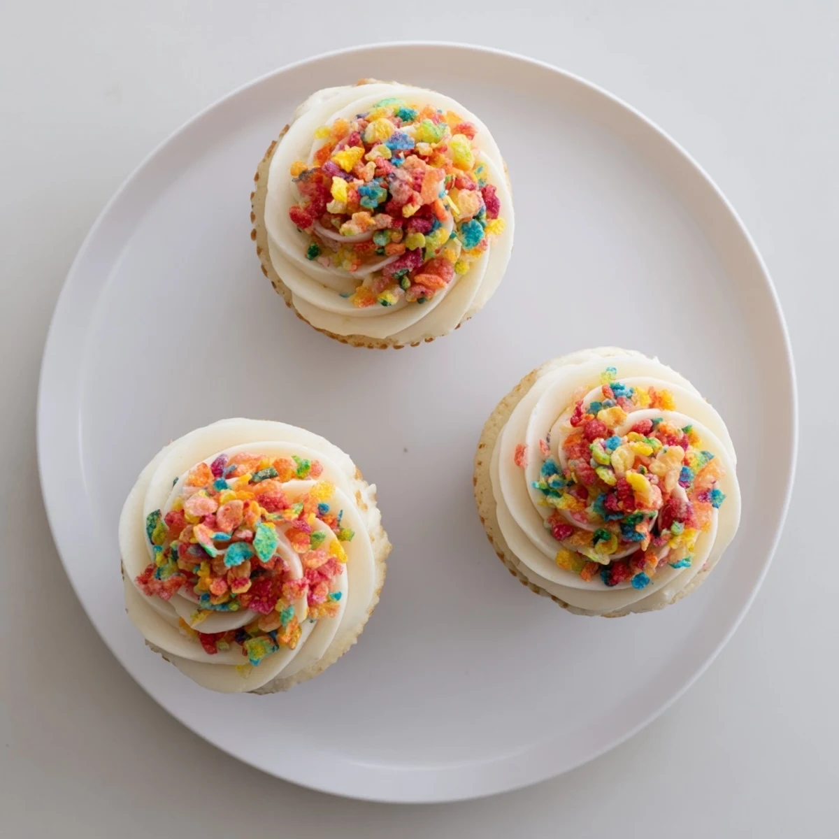 Fruity Pebbles Cereal Frosting piped atop vanilla cupcakes, creamy, colorful, crunchy garnish