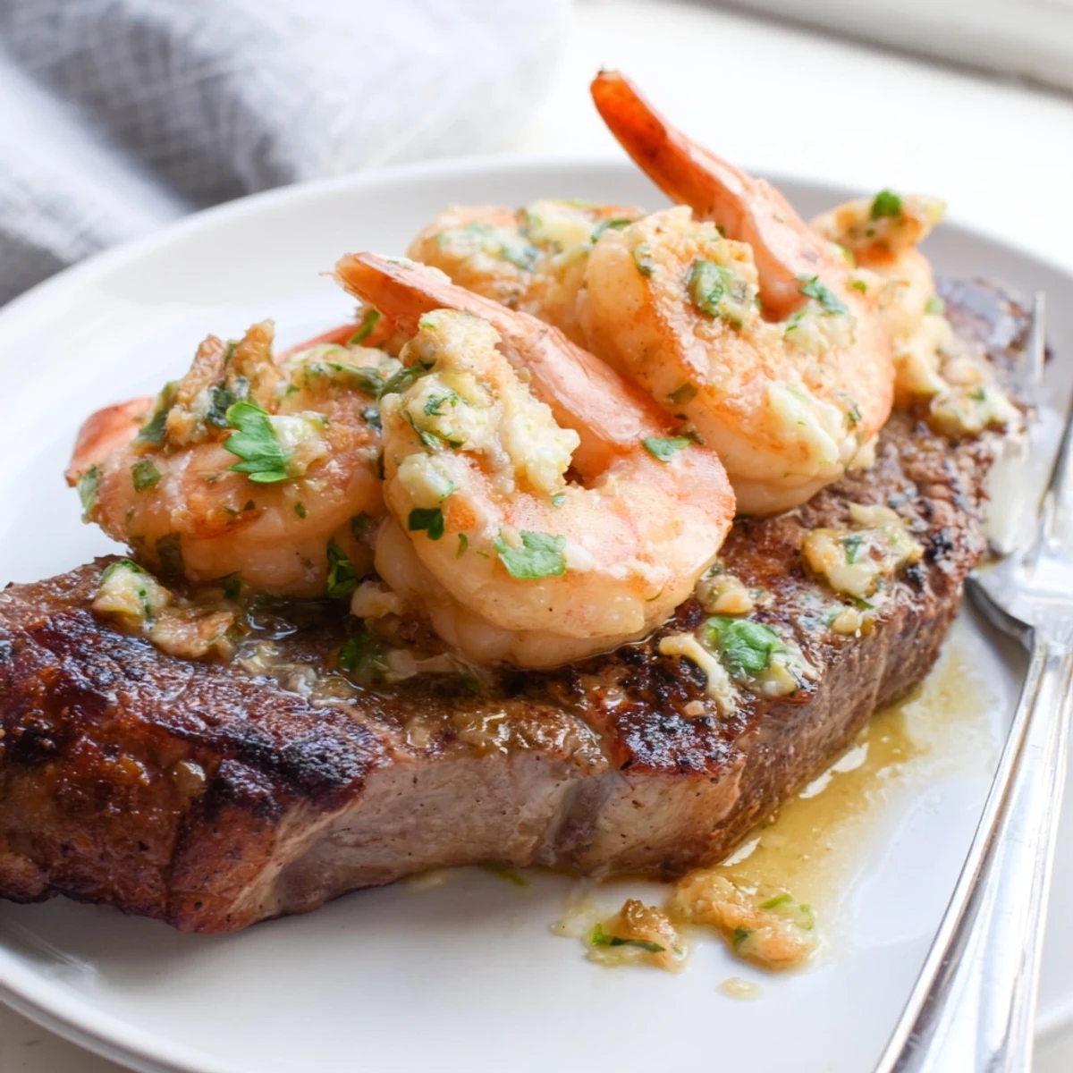 Tender ribeye steak topped with sizzling garlic butter shrimp in a cast iron skillet