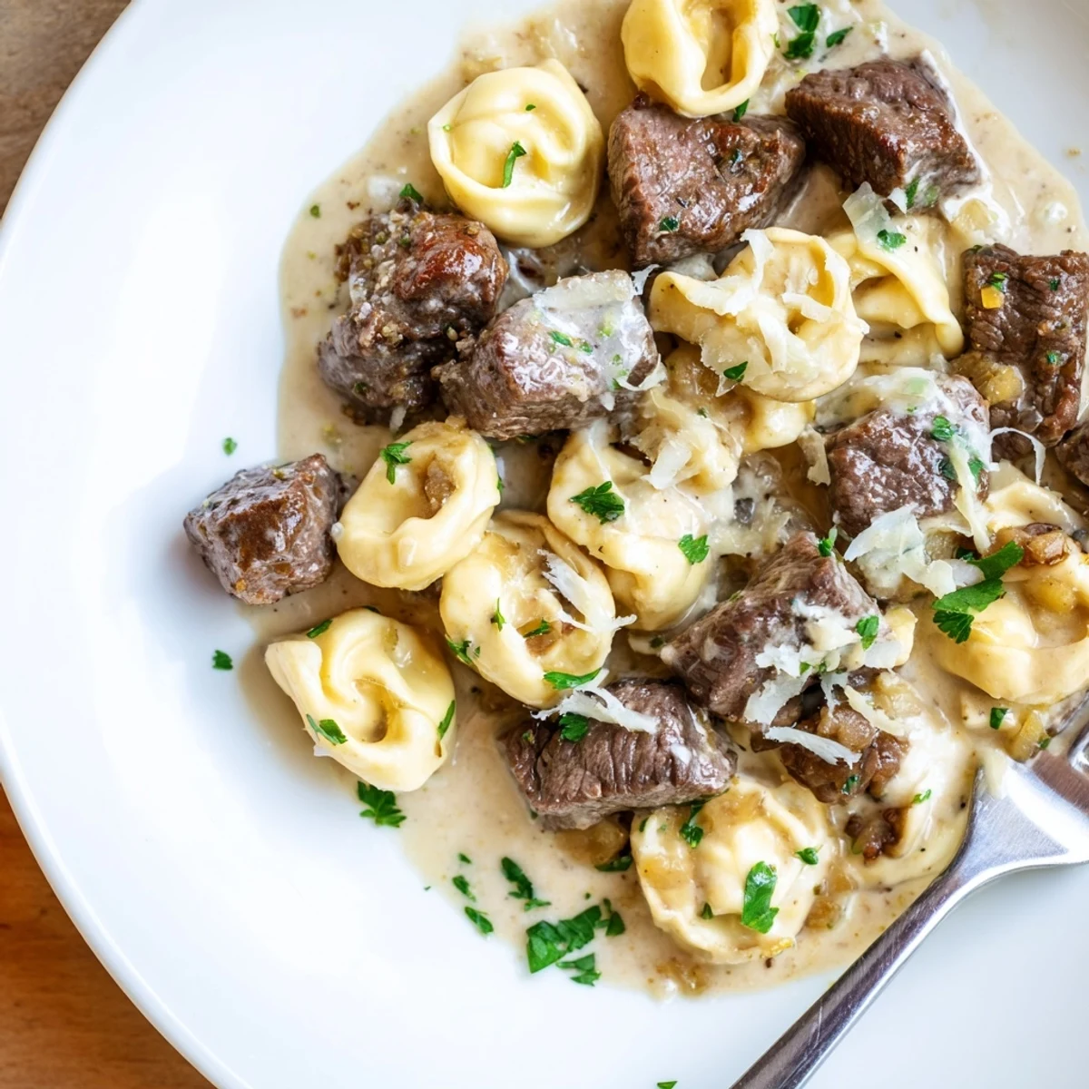 Savory garlic steak tortellini in creamy sauce with seared beef bites and parsley garnish.