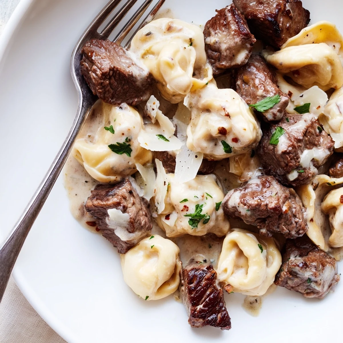 Bowl of garlic steak tortellini featuring rich cream sauce and browned sirloin bites.