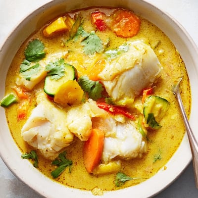Steaming bowl of coconut white fish stew ladled over fluffy jasmine rice