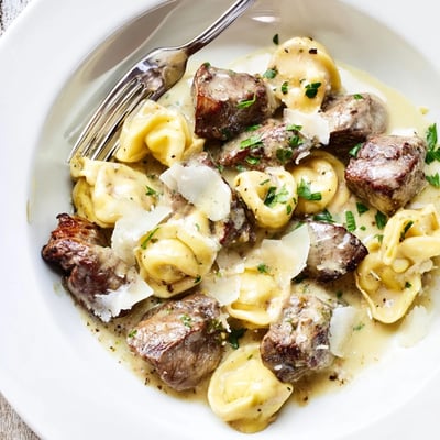 Creamy garlic steak tortellini plated with tender beef and parmesan coating pasta pieces.